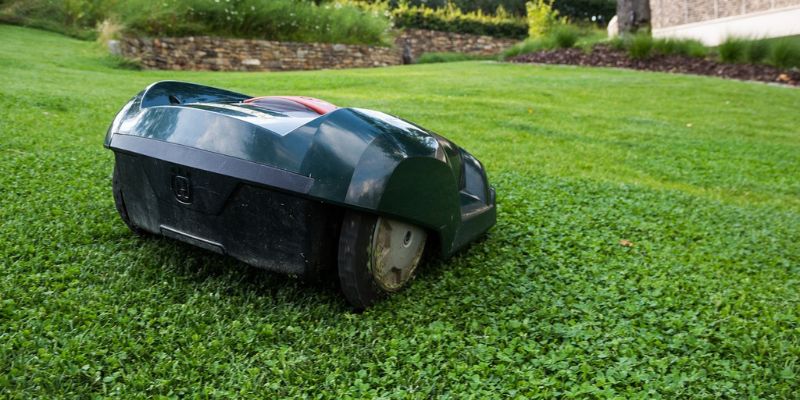 Moderne robot grasmaaier maait automatisch het groene gazon, met duidelijke maailijnen op de achtergrond.